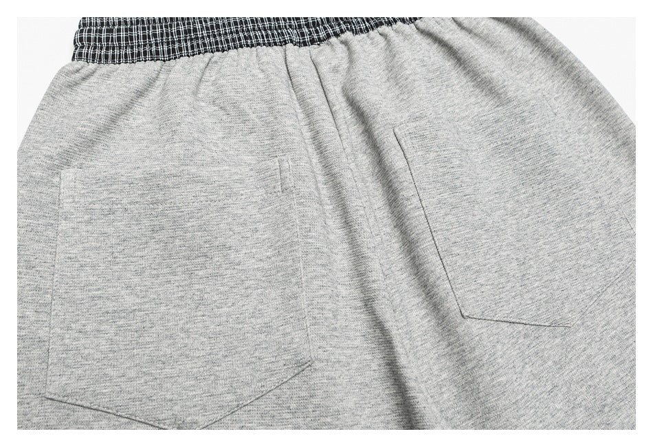 Rear view of heather-gray pants showing two patch pockets and a black-and-white plaid waistband.