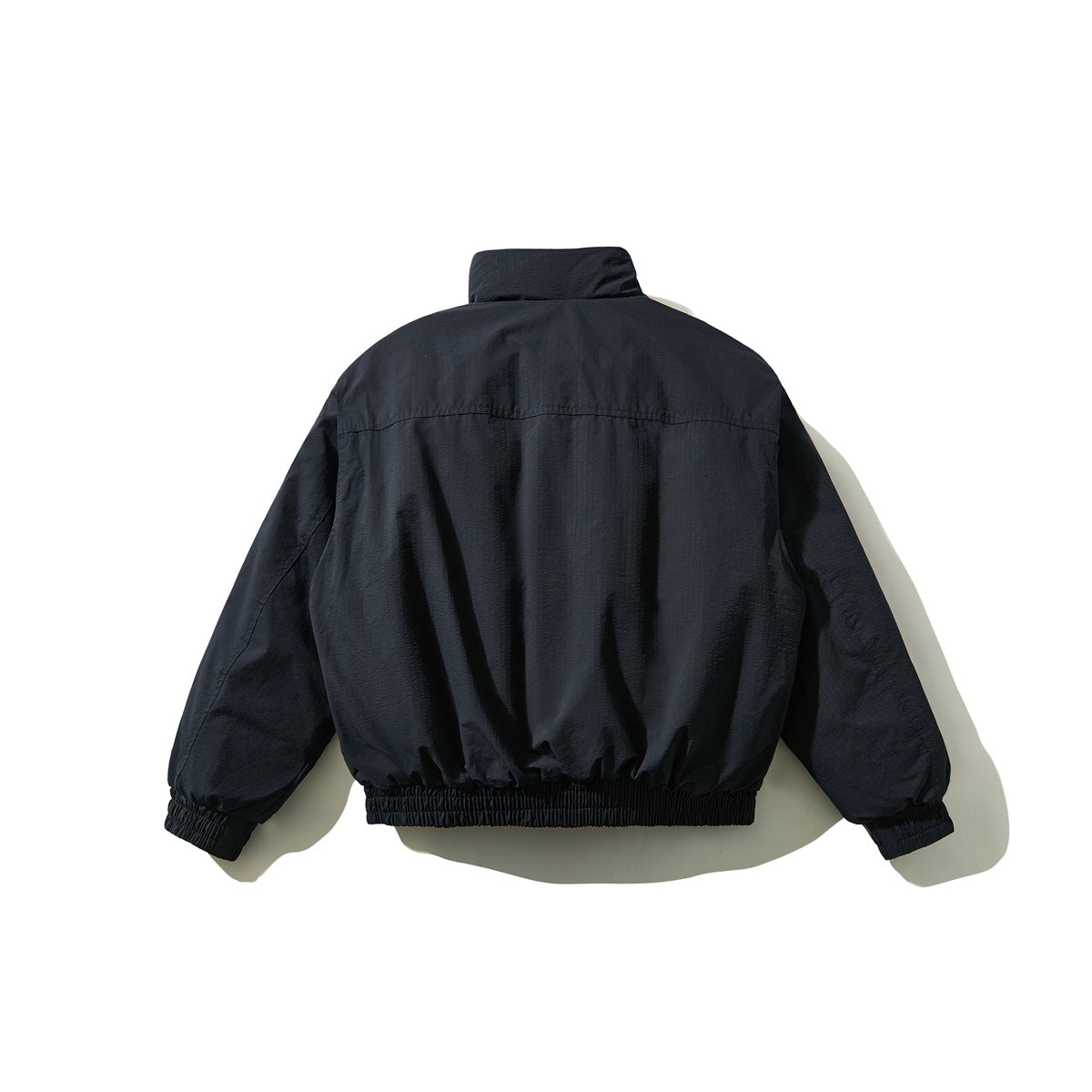 Back view of a dark navy jacket with a stand collar and gathered cuffs and hem.