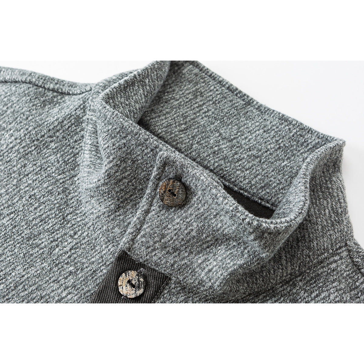 Close-up of a gray textured pullover's stand collar and mottled brown buttons.