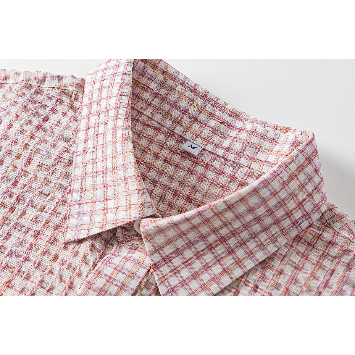 Close-up of a pointed collar on a cream shirt with pink and muted gold plaid; an M size tag is visible.