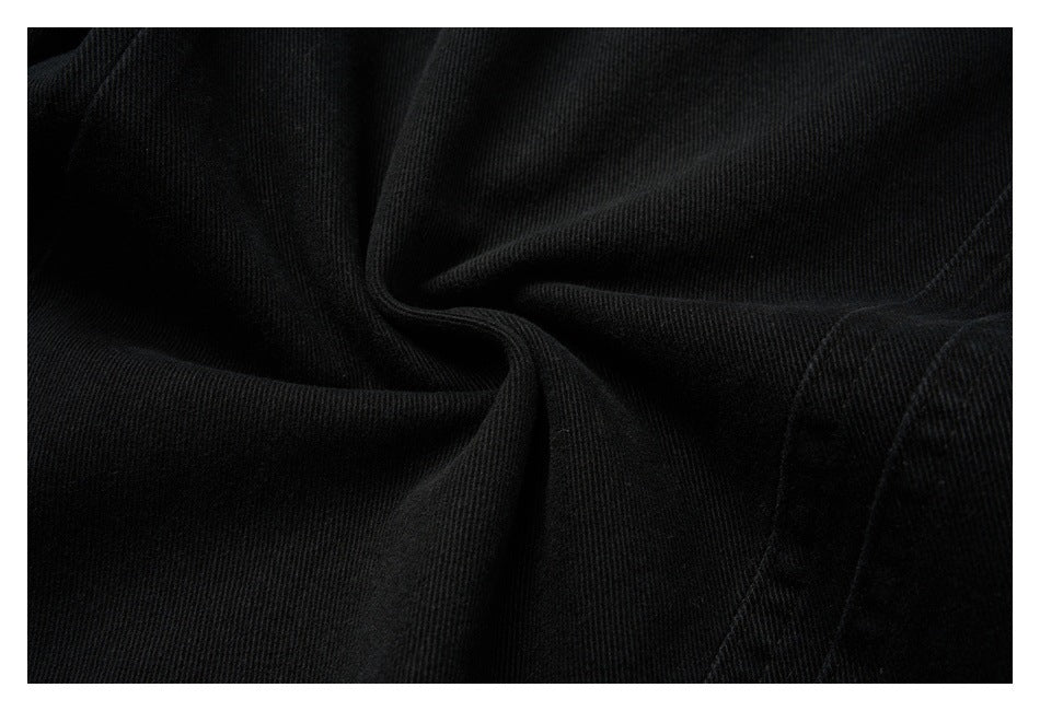 Close-up of black pants fabric draped into folds, with a stitched seam visible.