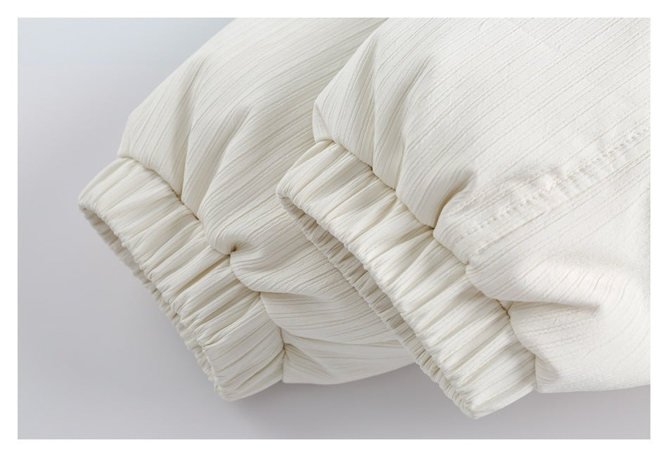 Close-up of gathered, elasticized cuffs on an ivory ribbed garment.