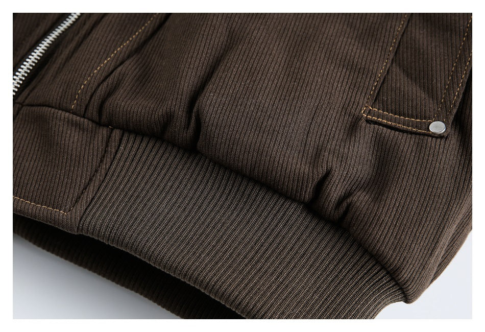 Close-up of a dark brown ribbed garment showing a ribbed hem, stitched pocket flap, and metal snap.