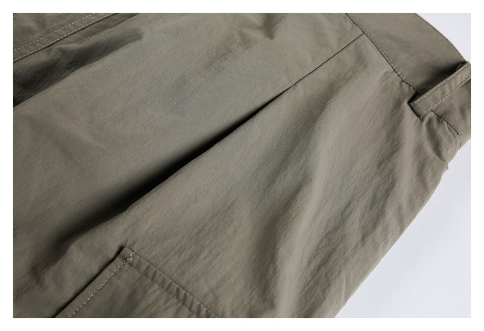 Close-up of olive-gray trousers with a stitched pocket edge and side seam.
