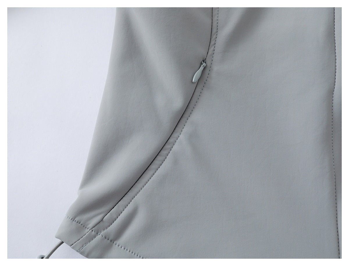 Close-up of a light gray garment showing a curved seam and small zipper pull.