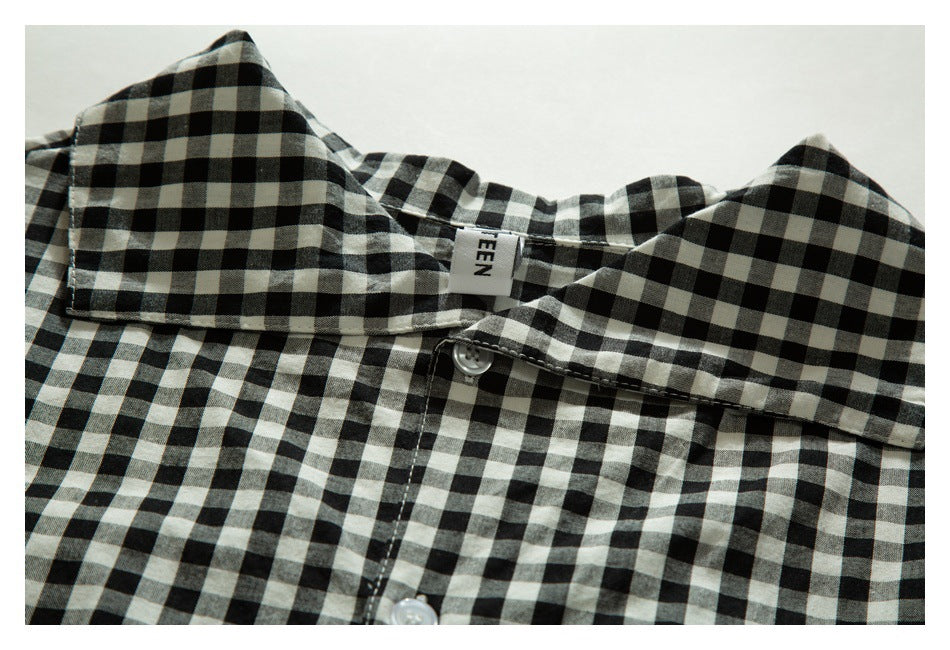 Close-up of a black-and-cream checked shirt collar, neck label, and white buttons.