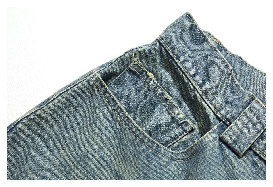 Close-up of light blue jeans showing a front pocket, waistband and belt loop.