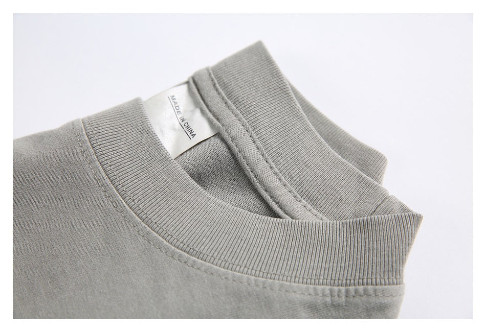 Close-up of the ribbed collar and inner label on a light gray garment; label reads “MADE IN CHINA.”