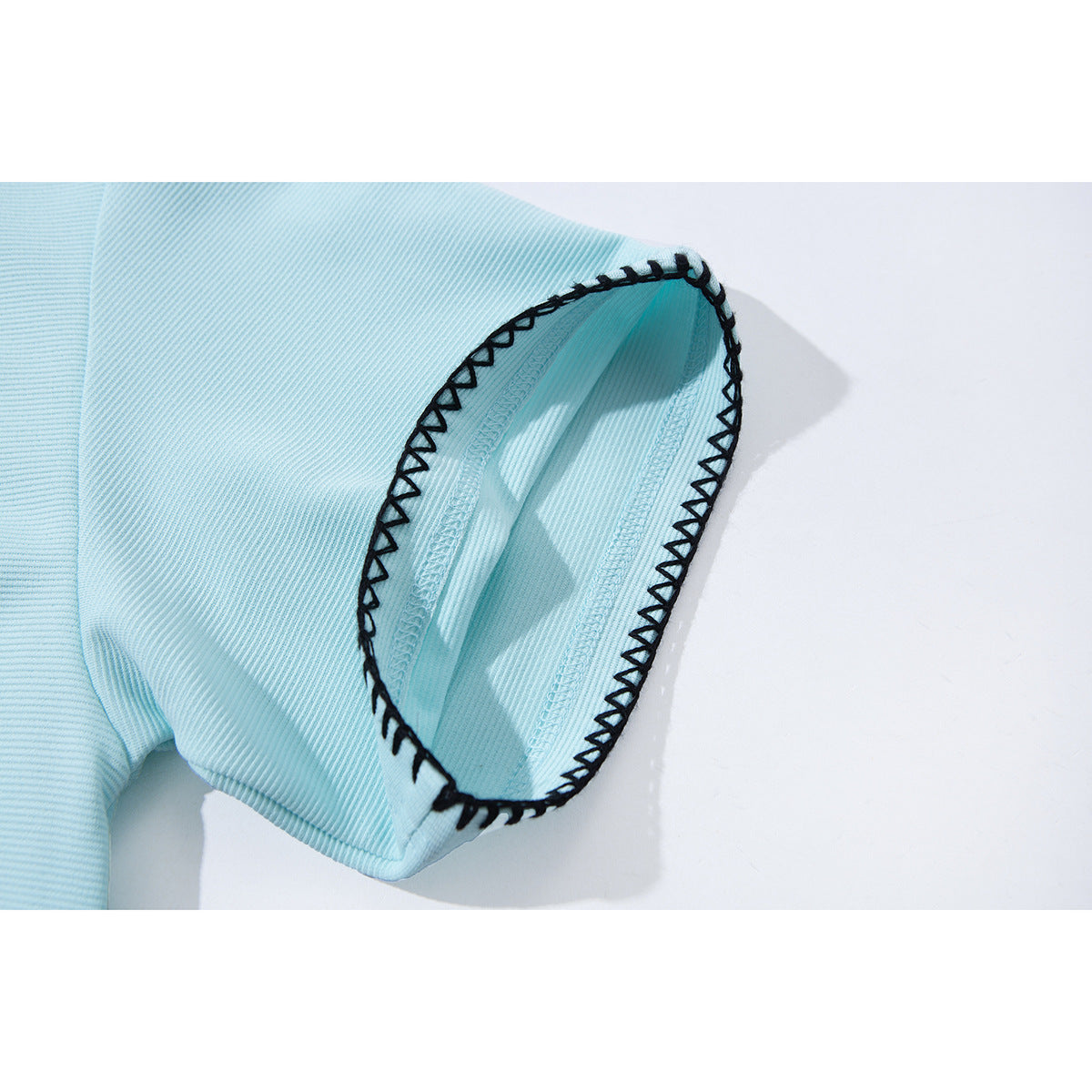 Close-up of a pale blue short-sleeve shirt cuff with bold black contrast stitching.
