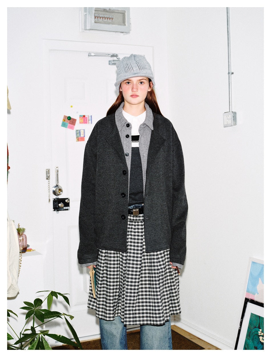 Front view of a model wearing a charcoal button-front jacket with a gray collar and cuffs over a dark top.