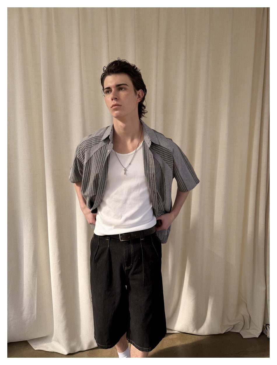 Model wearing an open gray striped short-sleeve button-up shirt over a white tank top.