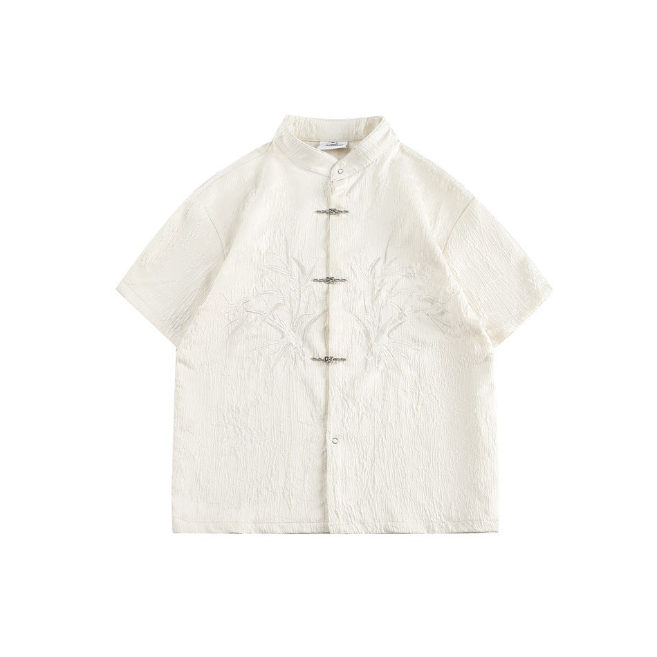 Beige short-sleeve stand-collar shirt with metal knot fastenings and embroidered bamboo leaves, flat front view