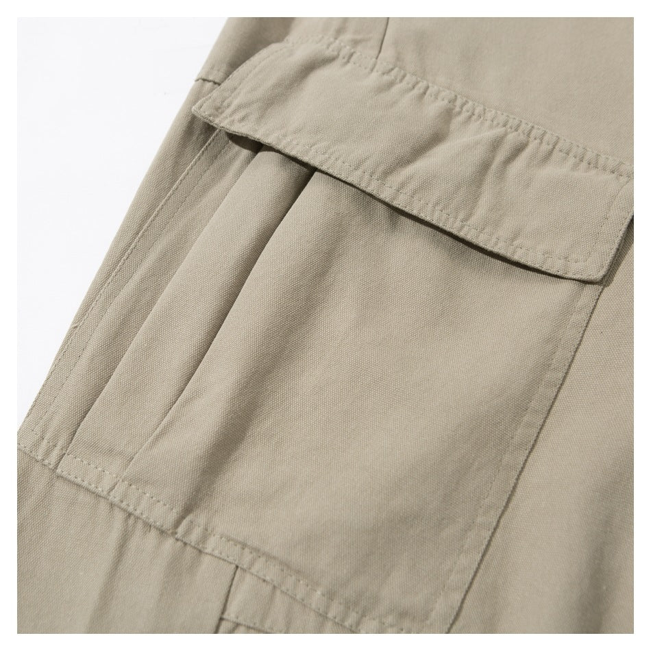 Close-up of beige trousers showing a large flap cargo pocket with stitched pleats.