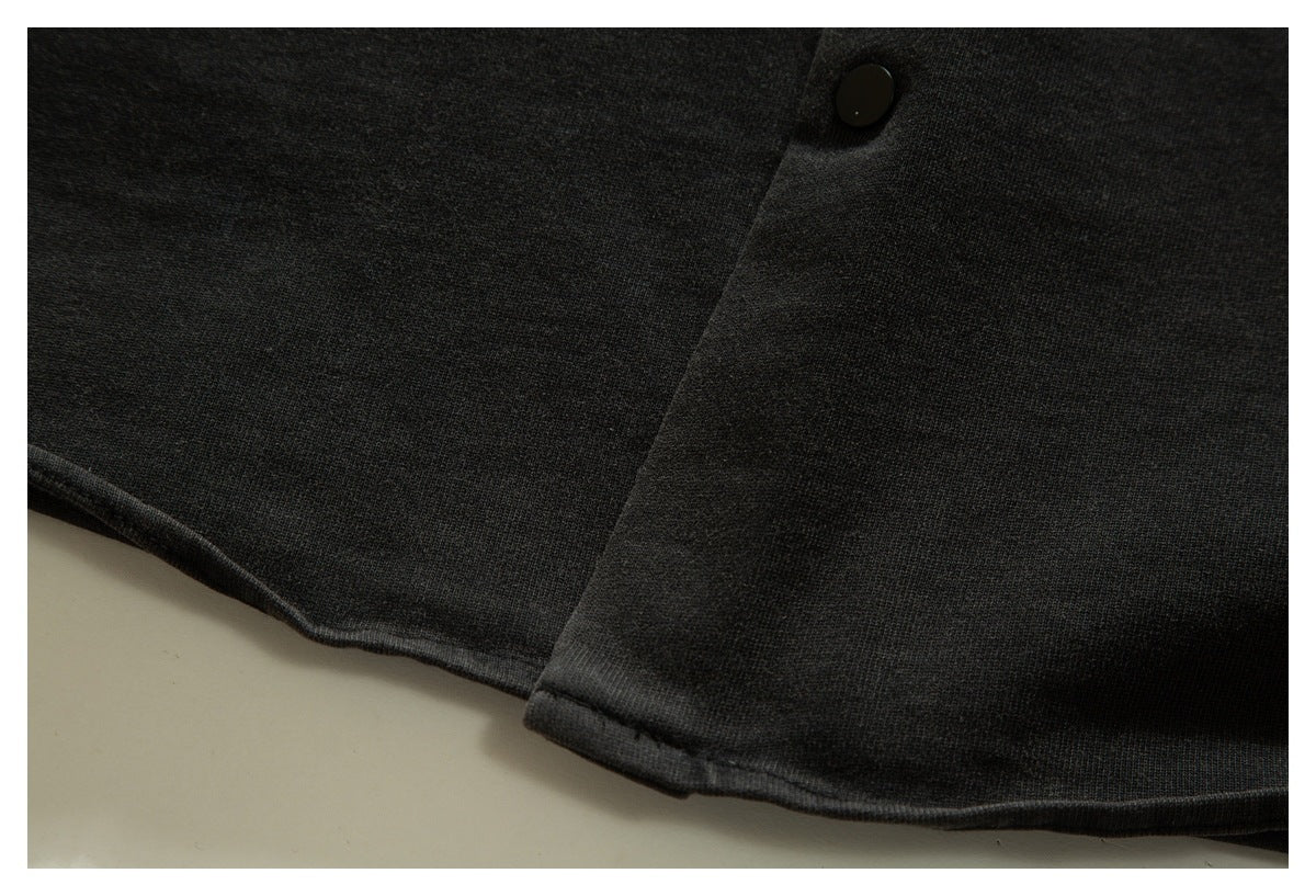 Close-up of black garment fabric, a stitched edge, and a small black button.