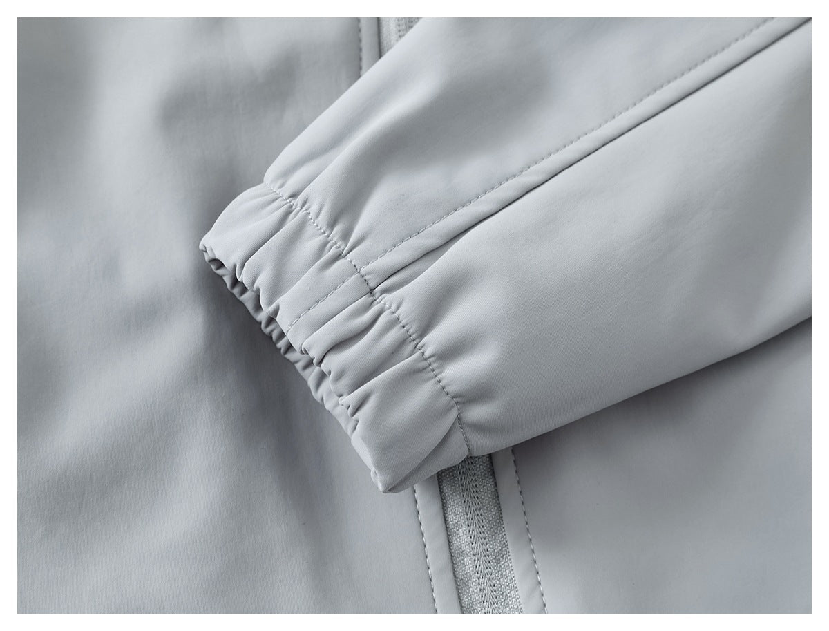 Close-up of a light gray garment sleeve with a gathered cuff, stitched seams, and a narrow zipper detail.