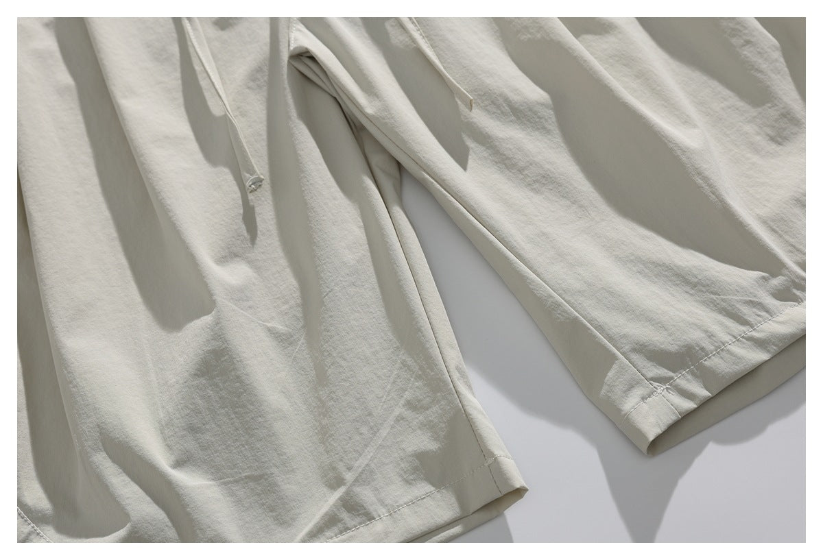 Close-up of the light ivory shorts' leg openings, stitched hems, and dangling drawstrings.