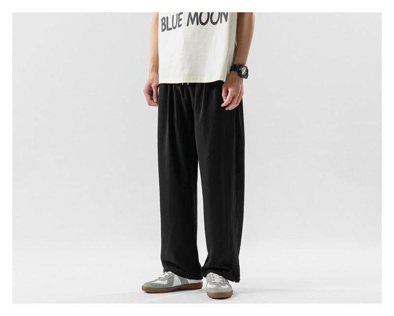 Front view of a model wearing loose black pants and gray sneakers; the white shirt has a BLUE MOON print.