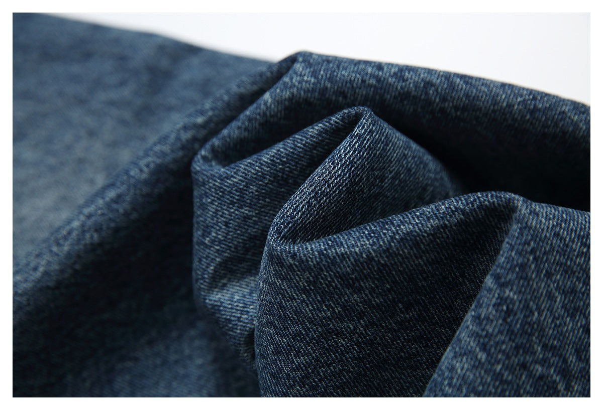 Macro view of dark blue denim folded to show its diagonal weave and texture.