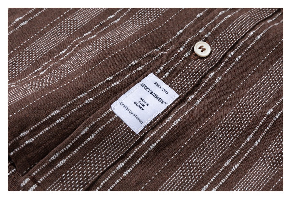 Close-up of brown fabric with narrow white stripes, a cream button, and a sewn English text label.