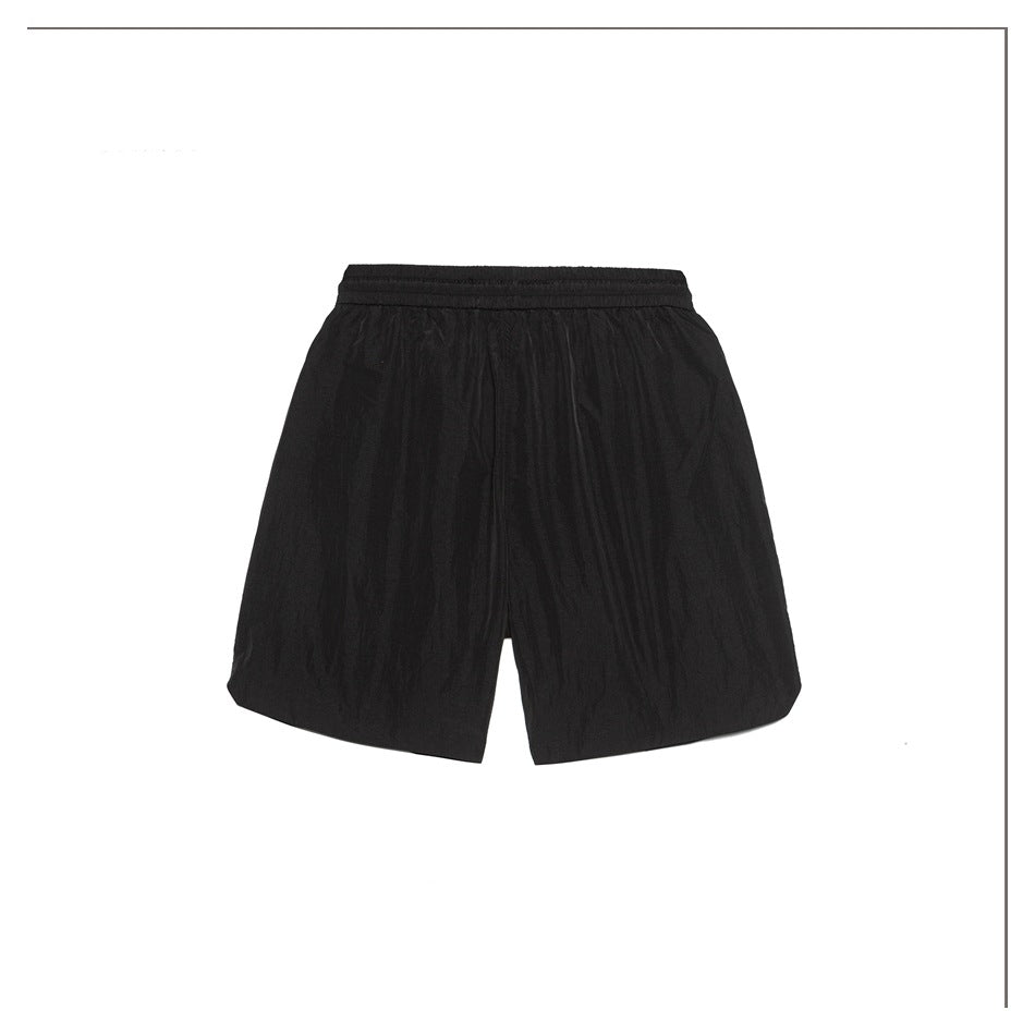 Back view of black crinkled drawstring shorts with elastic waistband and curved hem