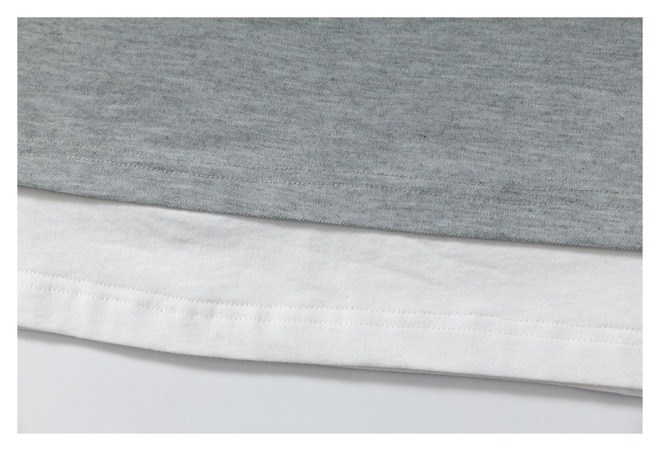 Close-up of a heather gray garment layered over a white hem, showing parallel stitching.