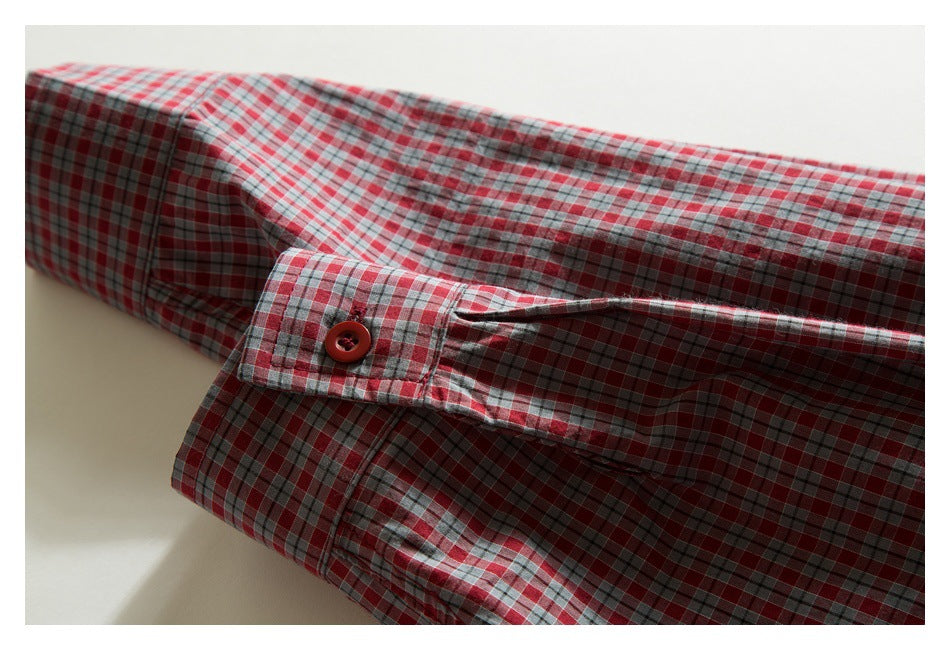 Close-up of a plaid shirt cuff with a red button and matching red, gray, and white checks.