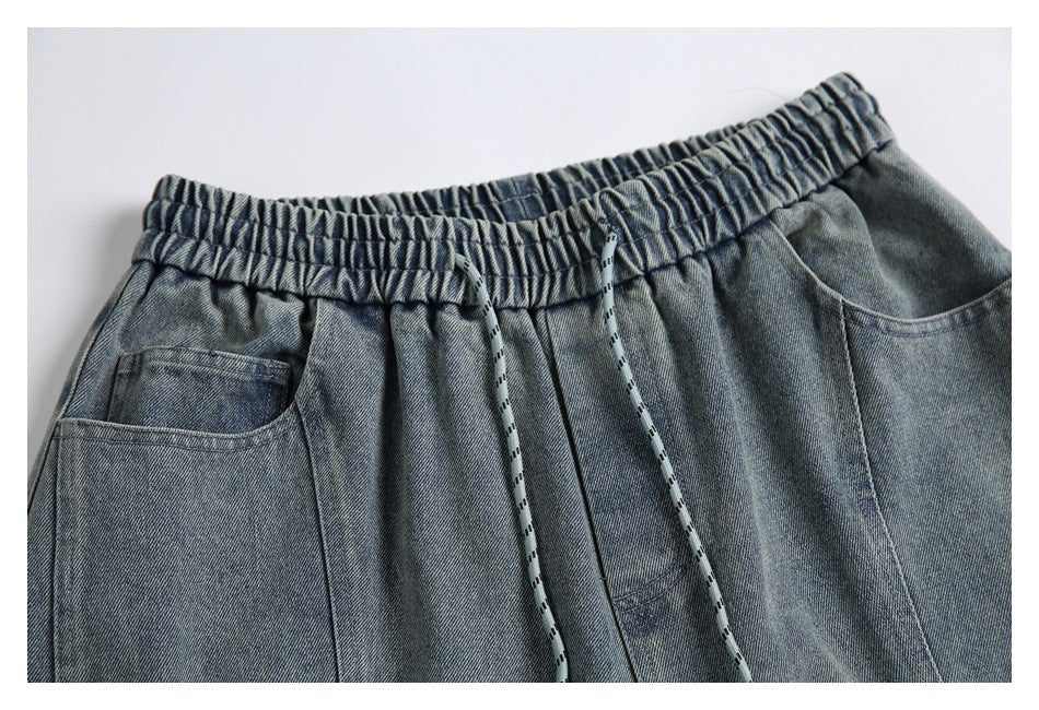 Close view of the denim shorts' elastic waistband, drawcord and front pockets.