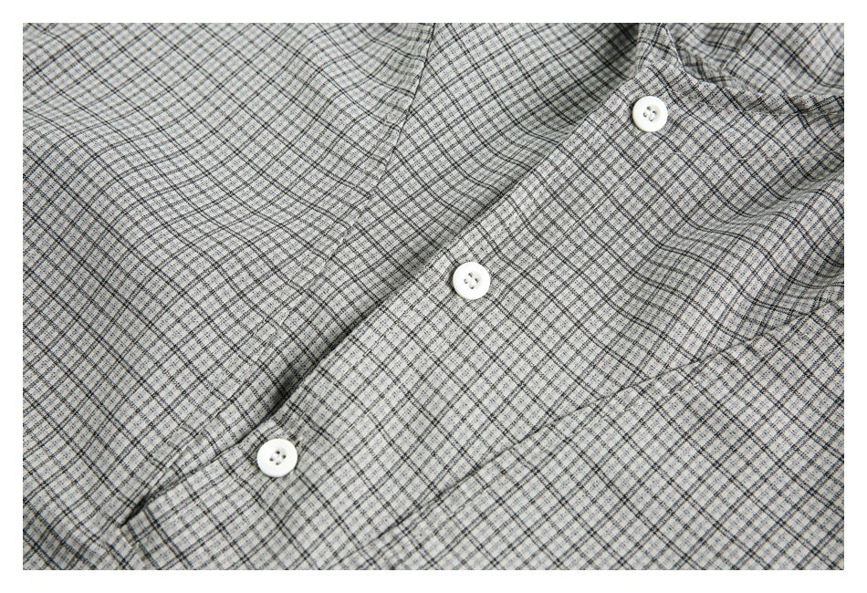 Close-up of the gray checked fabric and three white buttons on the pullover's front placket.