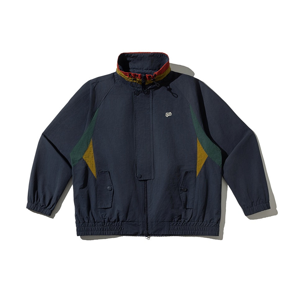 Navy stand-collar zip jacket flat lay with green and mustard side panels, flap pockets and elastic hem