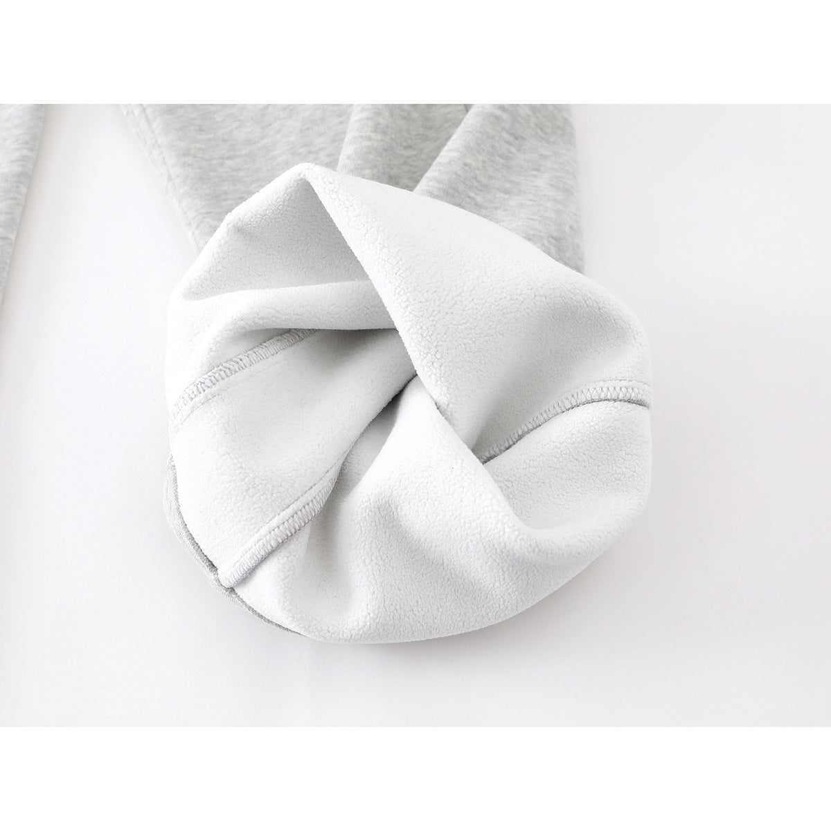 Close-up of the soft white fleece-like interior and stitching of light gray sweatpants.