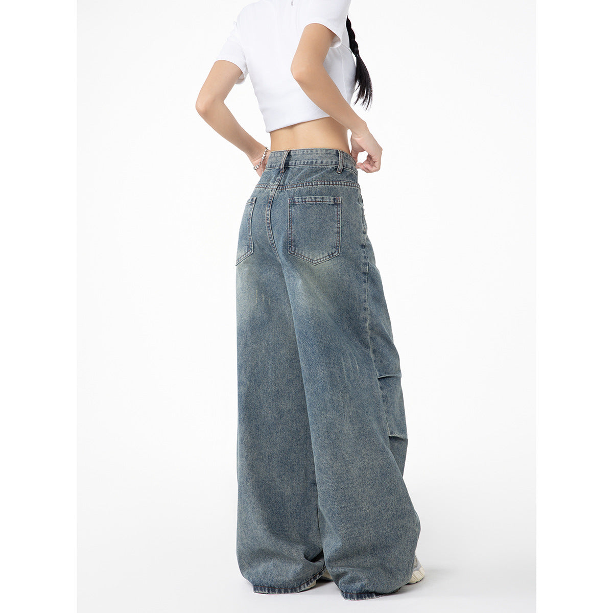 Rear view of a model wearing faded blue wide-leg jeans with two back pockets.