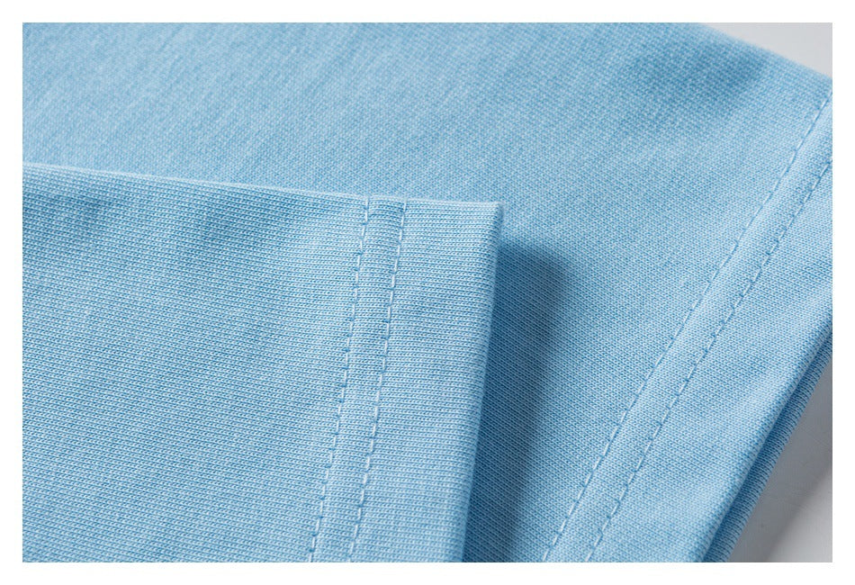 Close-up of light blue fabric with a stitched seam and folded edge.