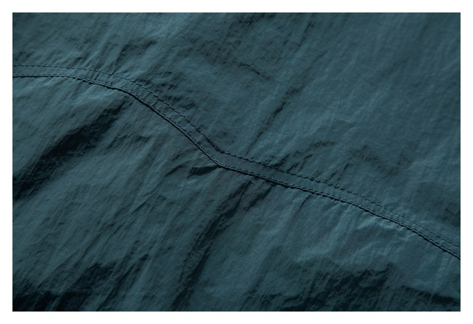 Close-up of a curved double-stitched seam on dark teal fabric.
