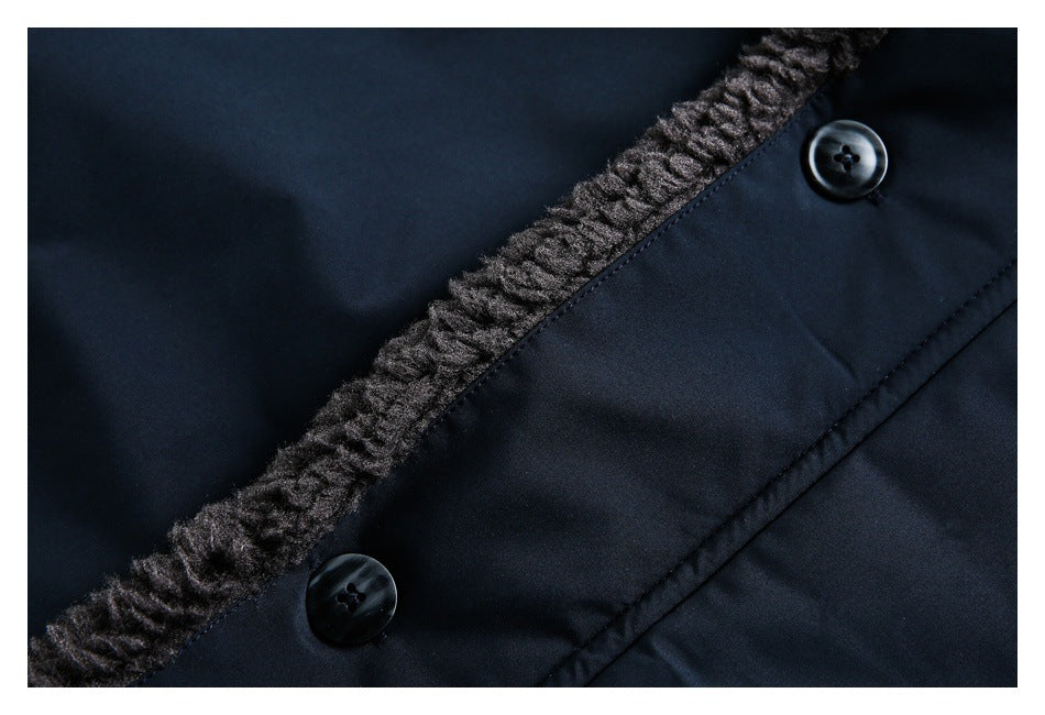 Close-up of a navy coat placket with two dark buttons beside charcoal fuzzy trim.