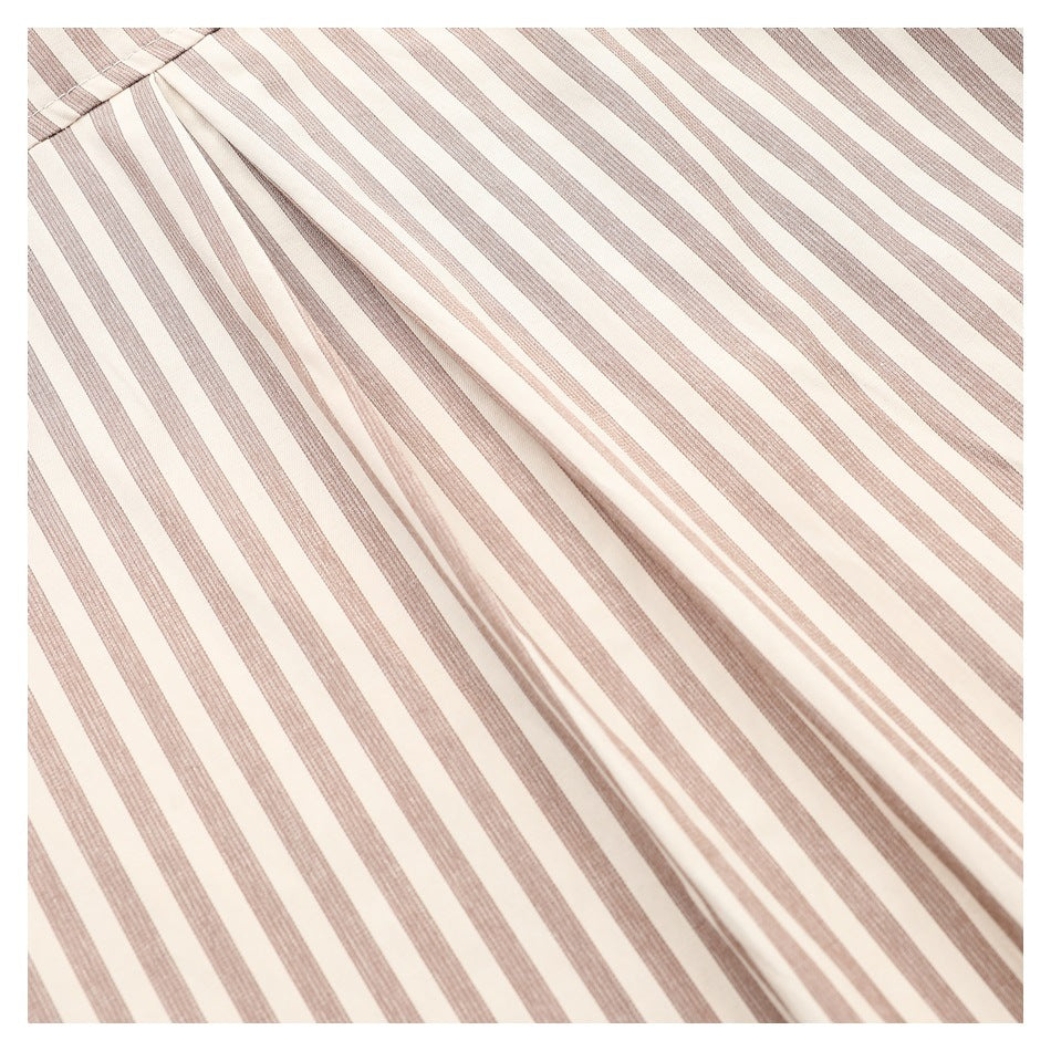 Close-up of cream fabric with narrow taupe vertical stripes and a folded seam.