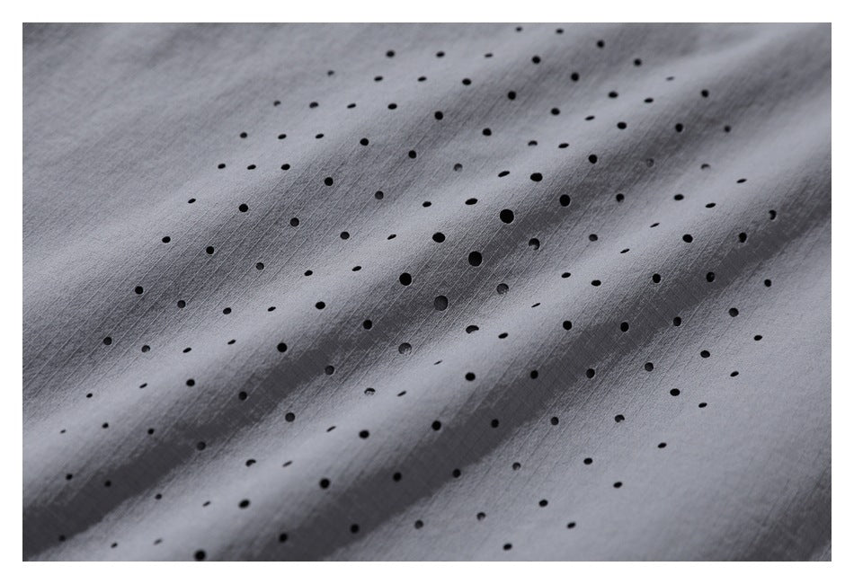Close-up of gray fabric with scattered small black perforations.