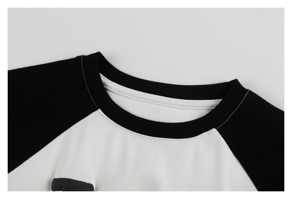 Close-up of a white raglan shirt's neckline with black collar and shoulder panels.