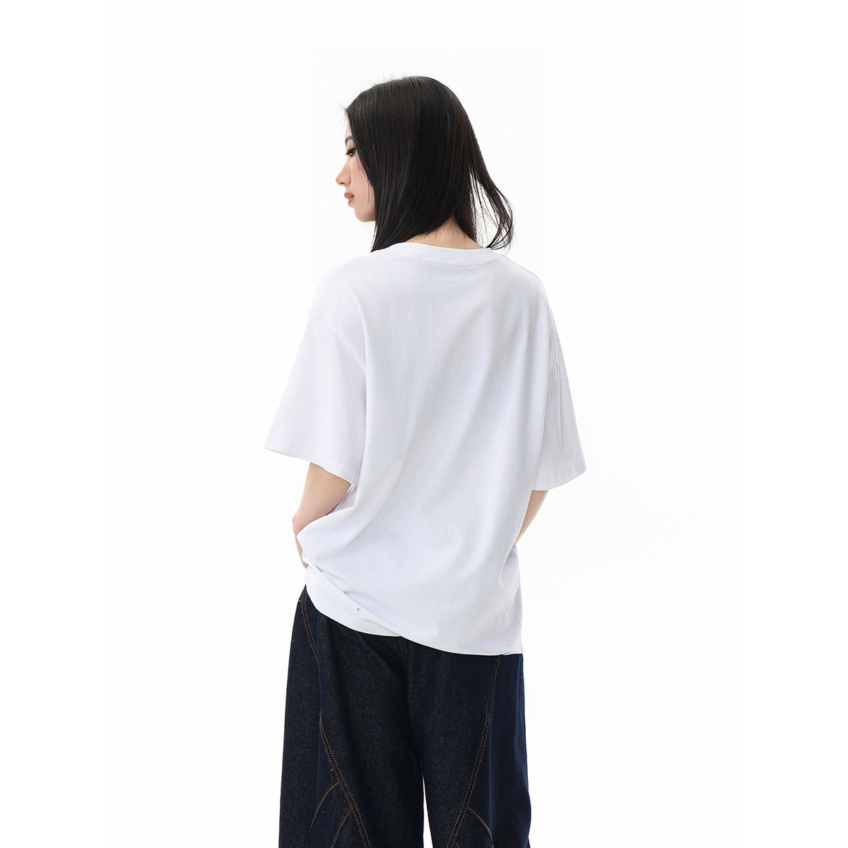 Model shown from behind in a plain white oversized T-shirt and dark loose jeans.