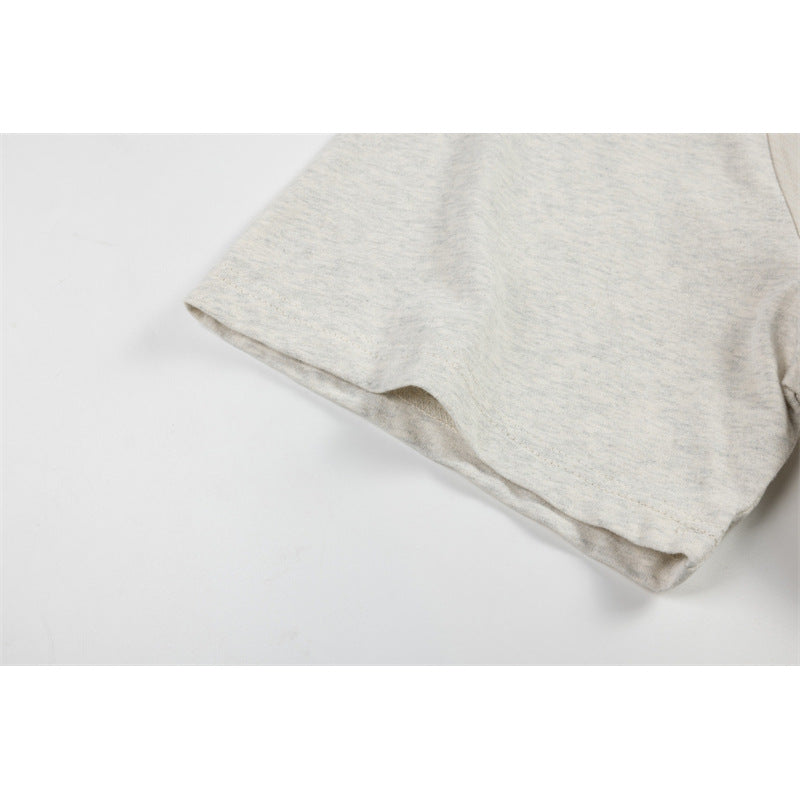 Close-up of the heathered light gray-beige short sleeve and hem of a T-shirt.
