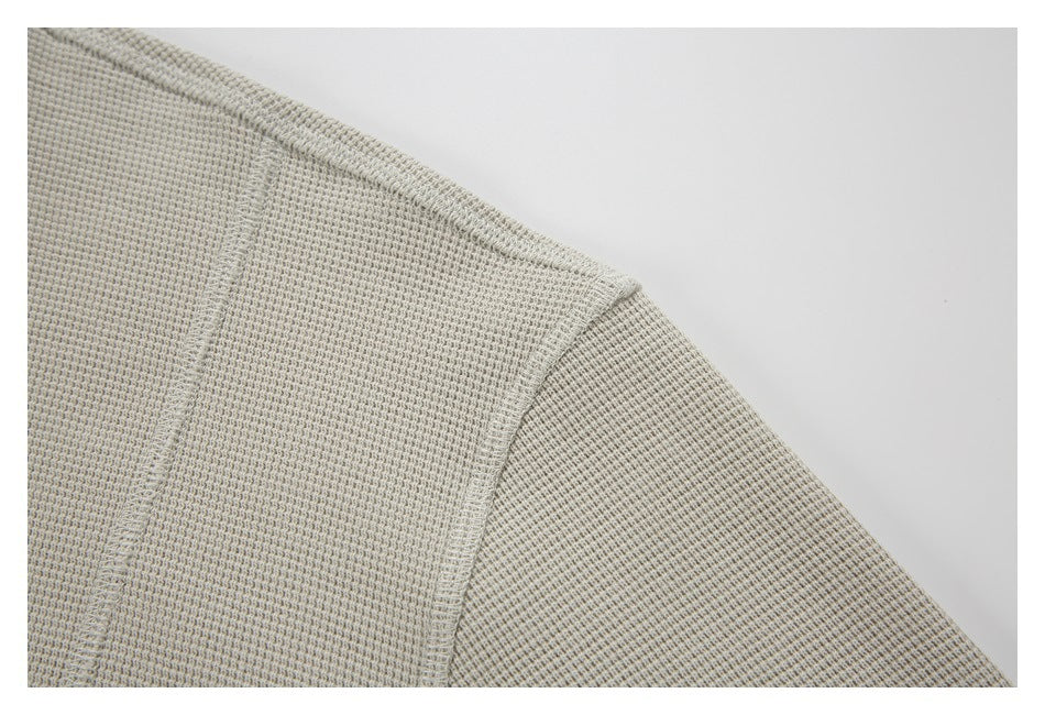 Close-up of the pullover's shoulder seam and textured light beige fabric.