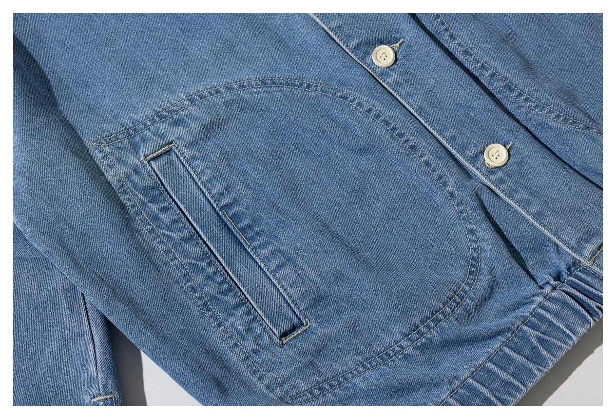 Close-up of a blue denim jacket front pocket, button placket, and contrast stitching.