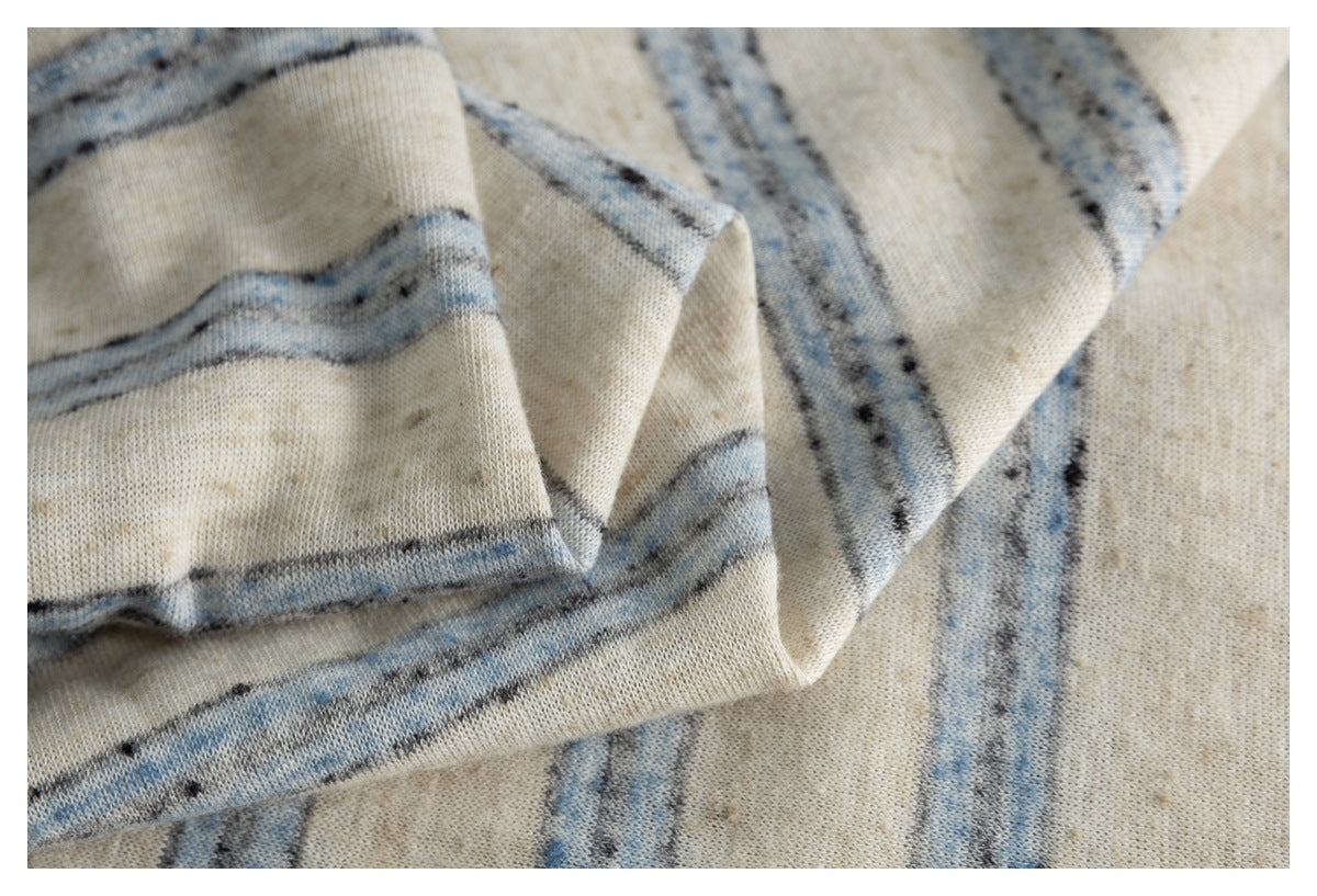 Close-up of layered, folded cream striped fabric showing its texture and stitching.