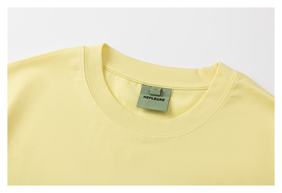 Close-up of a pale yellow T-shirt's ribbed crew neckline and sewn-in neck label.