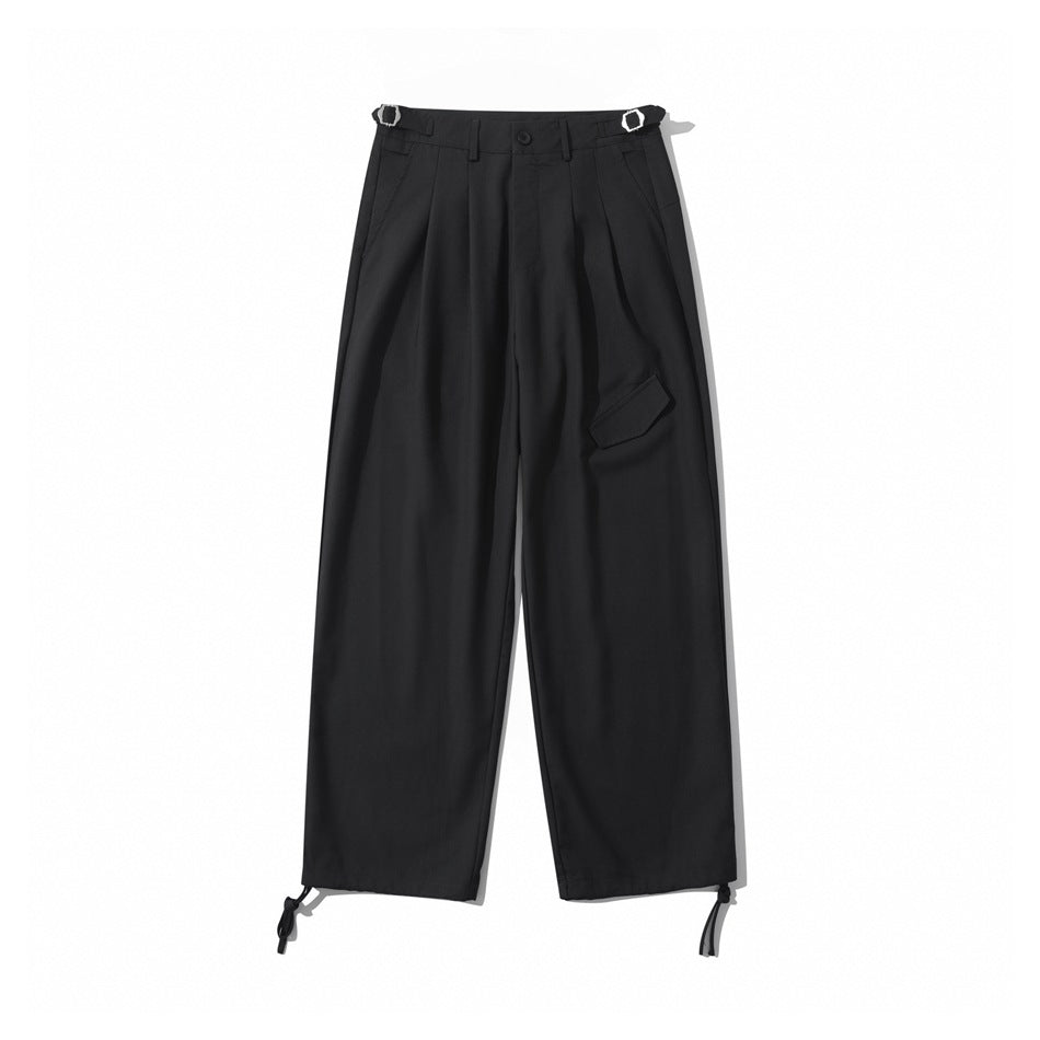 Black wide-leg pleated trousers flat lay with side buckle tabs, front flap detail and hem drawcords