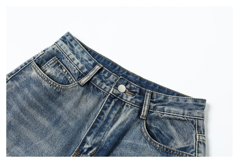 Cropped front view of blue acid-wash jeans, showing the waistband, button, belt loops and front pockets.