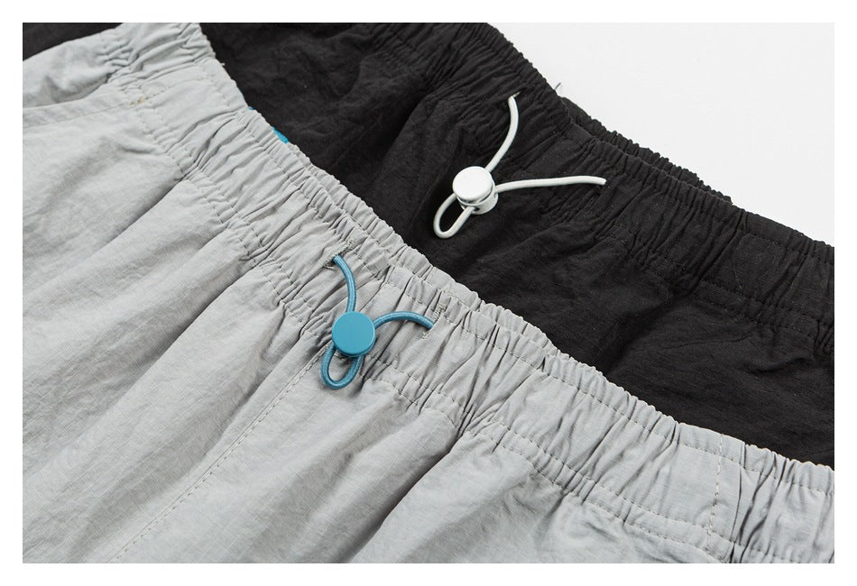 Close-up of gray and black shorts showing elastic waistbands and adjustable drawcords.
