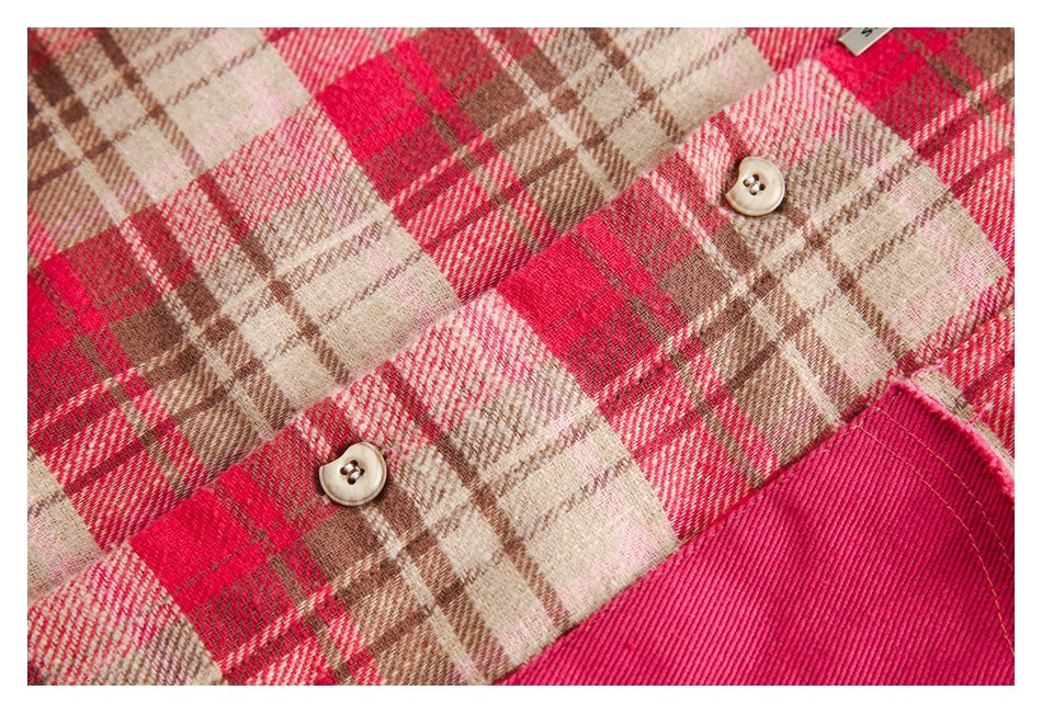 Close-up of cream buttons and a bright pink pocket on a red, cream, and brown plaid garment.