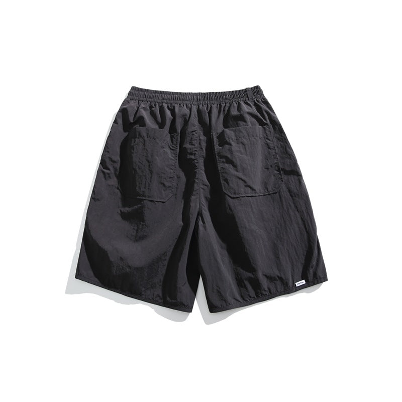 Front view of dark charcoal shorts with an elastic waistband, drawstring, and two large patch pockets.