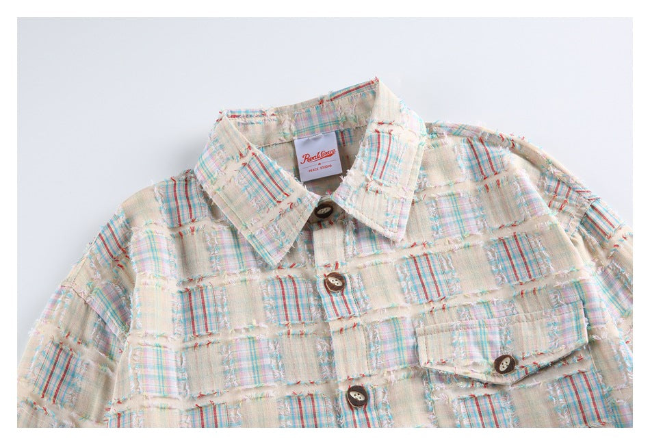 Close-up of the shirt's collar, buttons, and chest pocket in cream multicolor plaid patchwork; inner label visible.