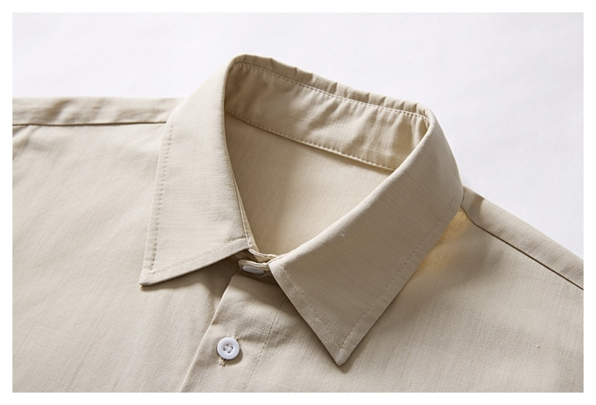 Close-up of a beige short-sleeve shirt showing its pointed collar, white button, and front placket.